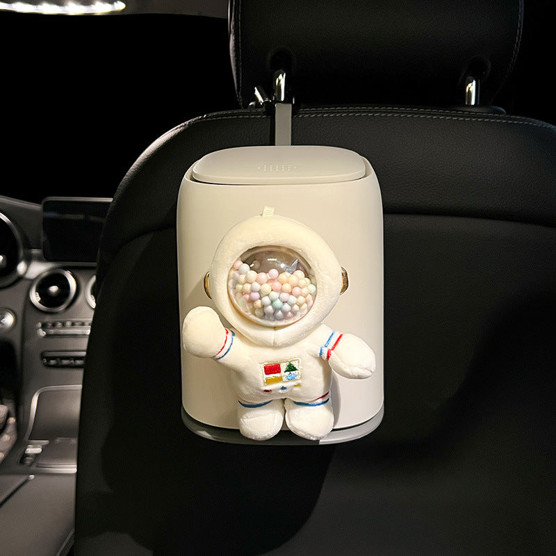 Car air freshener shaped like an astronaut with a gumball machine design inside, mounted on a car's headrest.