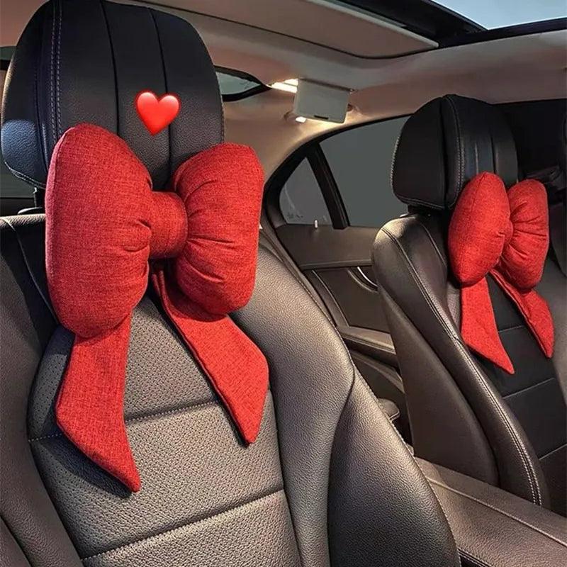 Red bow-shaped car headrest covers on a car seat interior.
